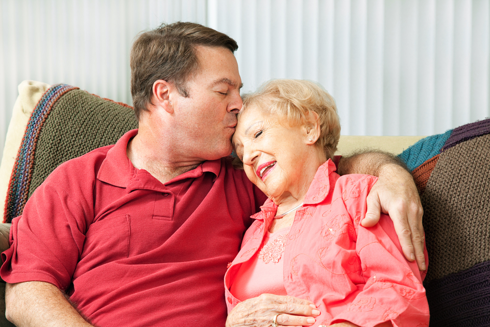 adult child holding hands with an elderly parent
